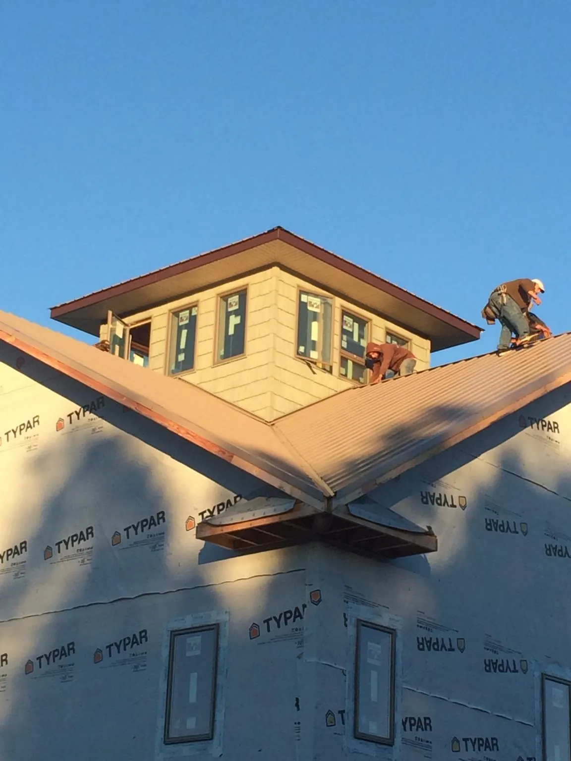 Roofers working around a rooftop cupola on a new metal roof at sunset — Roof Waterproofing in Parker by Roofing Brothers